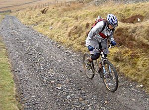 A cross-country mountain biker climbs on an un...
